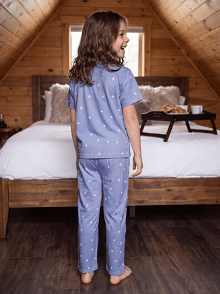 GIRLS, standing by a bed, wearing a light blue polka dot pajama set.