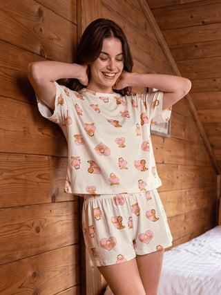 A woman poses wearing a cream-colored pajama set with a Garfield and heart print.