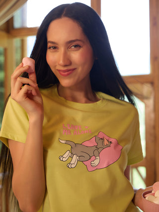 A woman in a light yellow t-shirt with a "Leave Me Alone" Tom and Jerry print, holding a marshmallow.