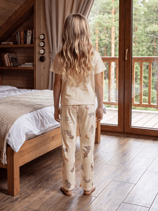 girl wearing a cream colored pajama set with cartoon character print.