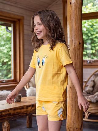 GIRLS in yellow Tweety Bird pajamas, standing, smiling.