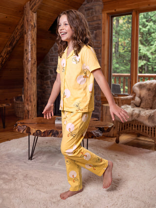 Girls in yellow Tweety Bird print pajamas, posed with one leg bent as if dancing.