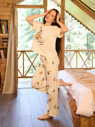 A woman poses playfully in a cream pajama set with a "Morning Duck" graphic and duck prints on the pants.