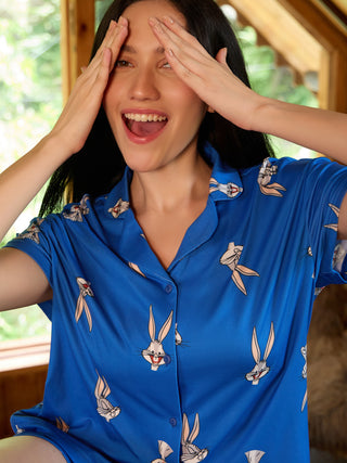 Women in a playful pose wearing blue Bugs Bunny print sleepwear.