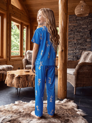 A young girl stands facing away from the camera, wearing blue Bugs Bunny pajamas.
