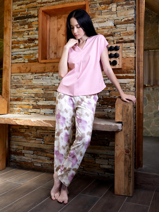 A woman models pink v-neck short-sleeved pajamas with a pastel floral print.