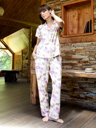 Women's pajama set with a pastel tie-dye print, featuring a collared button-down top and matching pants, shown with the model standing with one hand behind her head.
