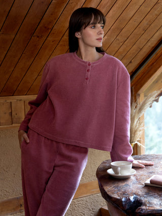 A woman poses in a pink waffle-knit pajama set.