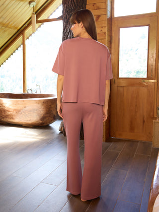 Women's loose fit mauve pajama set, standing facing away from the camera.
