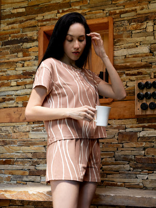 A woman in a brown striped pajama set holds a mug, with a subtle difference in background elements.