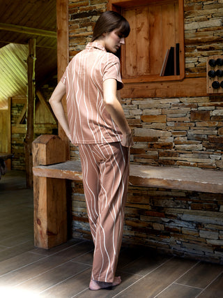 Women in a relaxed pose wear brown striped pajama set.
