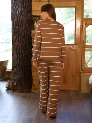 Women wearing a brown and white striped pajama set, standing with her back to the camera.