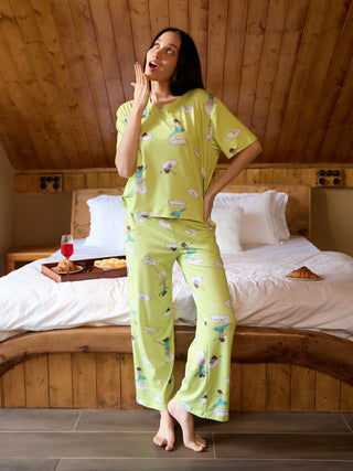 Women's light green pajama set with a playful yoga print, standing with hand raised to chin.
