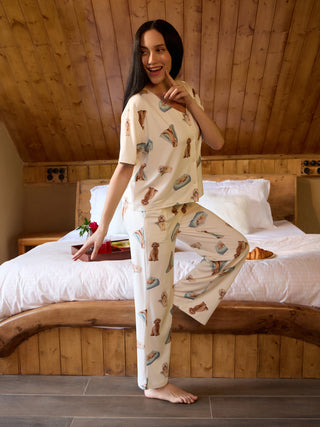A woman poses in a cream-colored pajama set featuring a playful dog print.