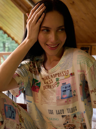 A woman in pajamas with a newspaper print featuring coffee and kitchen scenes.