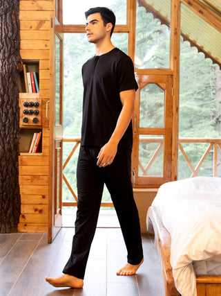 Men in black loungewear walking towards a bed.