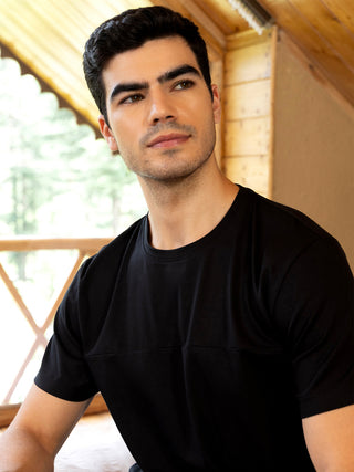 Men in a black t-shirt posing for a sleepwear company; this image is similar to the previous one but features a t-shirt instead of a button-down shirt.