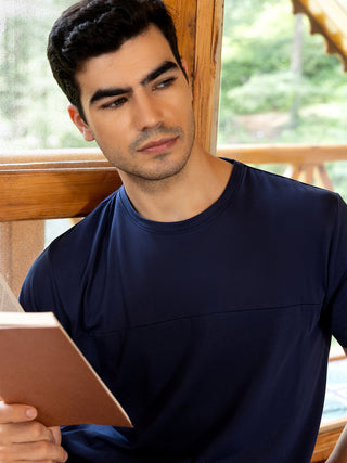 A man in a navy blue t-shirt is reading a book.