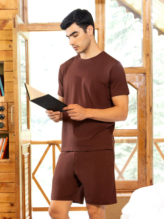 Men's brown solid t-shirt and shorts set, standing and reading a book.