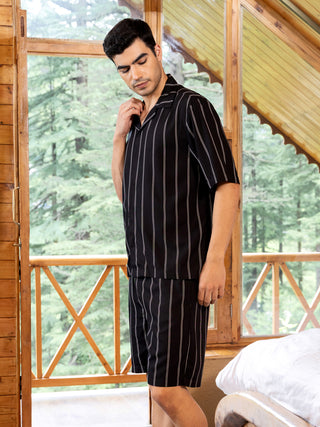 Men in a relaxed pose wear a black and white striped short-sleeved shirt and shorts set.