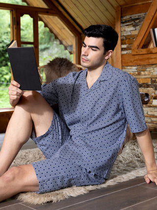 Men's navy blue patterned sleepwear set, worn casually while reading a book indoors.