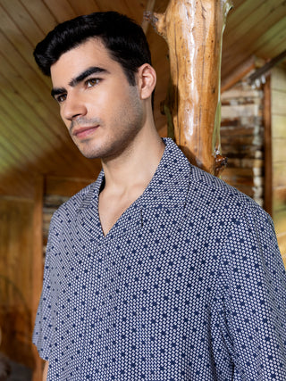 Men in a short-sleeved sleep shirt with a dark blue and white geometric print, posed looking to the side.