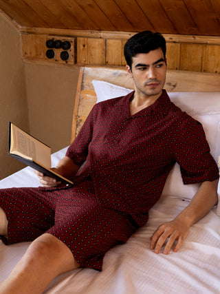 Men's maroon printed pajama set with a book in hand.