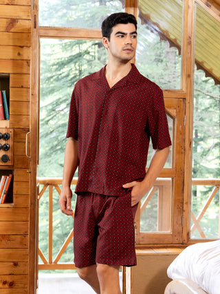 A young man poses in a maroon printed pajama set.
