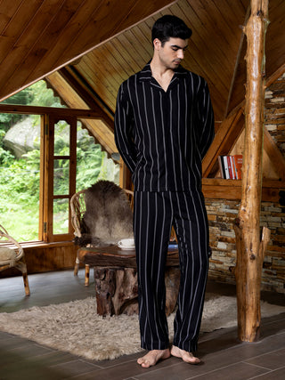 Men in black and white striped pajamas stand in a rustic room.