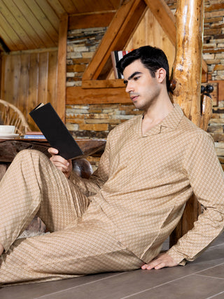 Men sitting cross-legged wearing light brown printed pajamas.