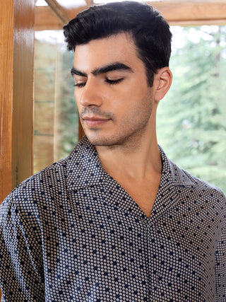 A man wears a navy blue printed sleep shirt.