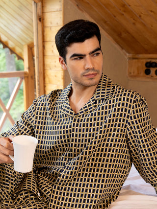 Men wearing a navy and gold geometric print pajama set, holding a white mug while looking away.
