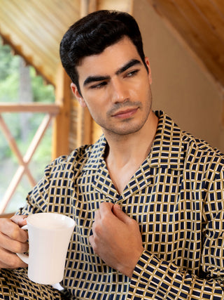 Men in yellow and black checkered pajamas holding a white mug.