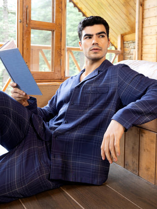 Men in dark blue plaid sleepwear reading a book.