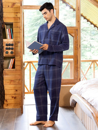 Men in navy blue plaid pajama set reading a book.