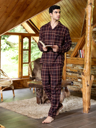Men wearing burgundy plaid pajamas, standing with a book.