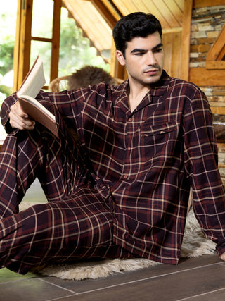 Men wearing maroon plaid pajama set, reading a book.