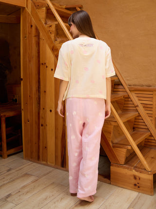 Women's light yellow polka dot pajama set with a pink "Tom and Jerry" graphic, standing with her back to the camera.