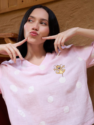 A young woman poses playfully in a pink polka dot pajama top with a Jerry print.