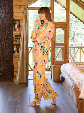 Women in a pink, yellow, and orange striped Looney Tunes print pajama set, standing and posing with a hand on her chin.