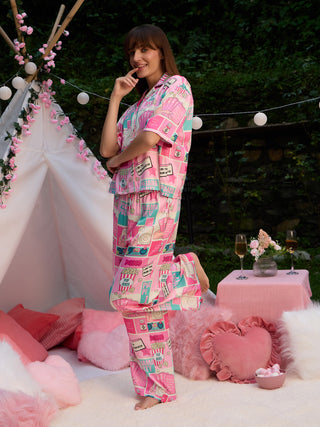 A woman poses playfully in pink, patterned pajamas featuring popcorn and playful text.