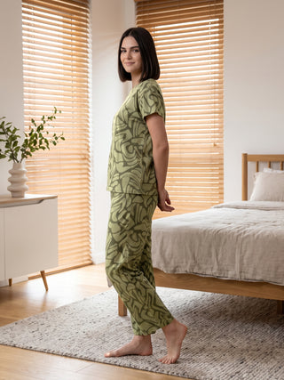 Women in a relaxed pose wearing a green abstract print pajama set.