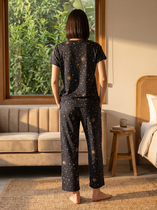 Women's dark blue printed pajama set with sun and moon motifs, standing with back to camera, similar to previous image but with a different print.