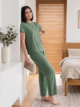 Women in a relaxed pose wear a green patterned loungewear set.