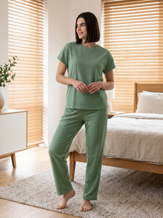 Women in a green patterned pajama set with a short-sleeved top and long pants.