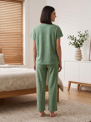 A woman from behind, wearing a sage green pajama set with a geometric arc print.