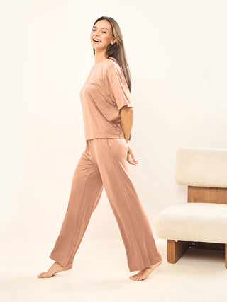a woman wearing brown nightwear walking around room.