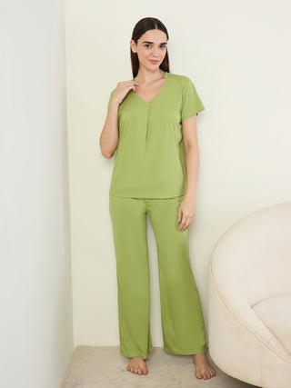 A woman stands posing in a green two-piece pajama set.