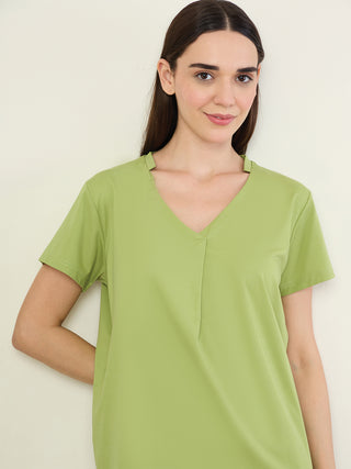 Women in a relaxed pose, wearing a light green V-neck t-shirt dress.