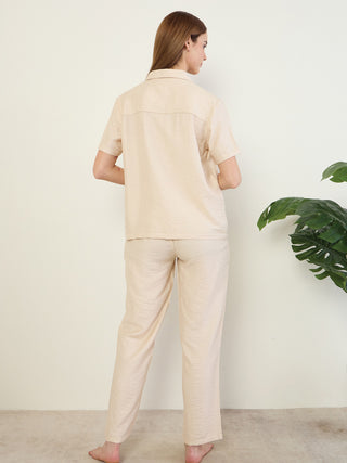 Women in a light beige pajama set, posing from the back, with a slight texture to the fabric.
